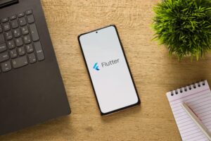 Um smartphone que exibe em destaque o logo do Flutter na tela.