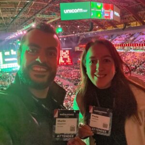 Paula Cárdenas, Gerente de Desenvolvimento de Negócios, e Murilo Magalhães, Head de Operações, representando a empresa no Web Summit Lisboa, participando de discussões sobre inovação e tecnologia.