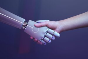 IA em seguros: Imagem de um robõ humanóide apertando a mão de um humano para exemplificar nosso artigo "Cinco formas de como a IA em Seguros melhora processos e reduz riscos.'.
